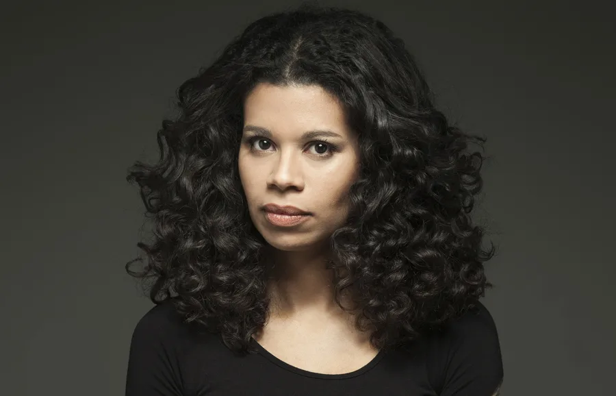 Ana Paula Maia em retrato com lombadas de seus livros ao fundo