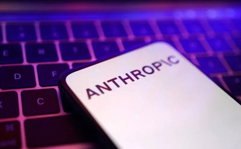 Celular com o logotipo da Anthropic na tela, apoiado sobre o teclado de um notebook iluminado por luz roxa