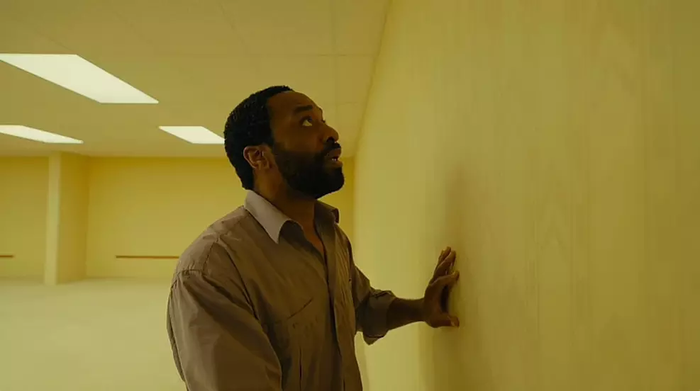 Corredor amarelado com carpete e iluminação fluorescente do filme Backrooms da A24