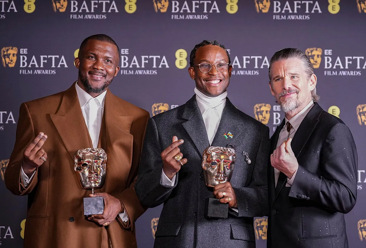 Akinola Davies Jr. no palco do BAFTA 2026 após receber o prêmio de melhor estreia britânica por A Sombra do Meu Pai