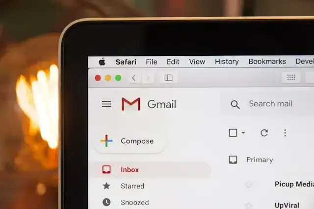 Interface do Gmail aberta no Safari em um MacBook, com fundo desfocado quente
