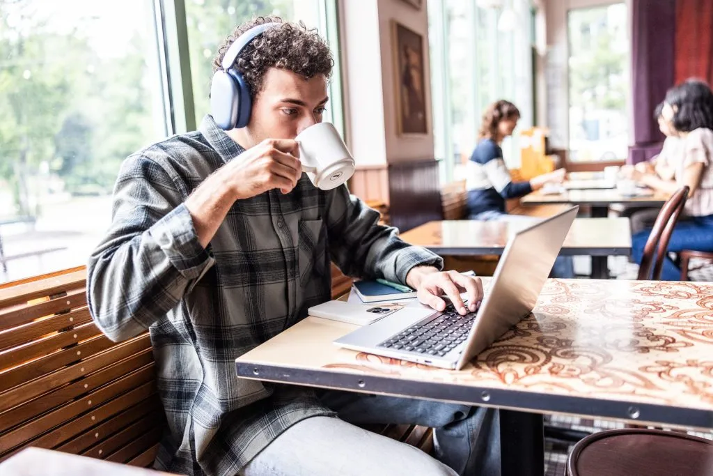 Jovem com laptop sentado em frente a uma porta fechada, representando barreiras de entrada no mercado de trabalho