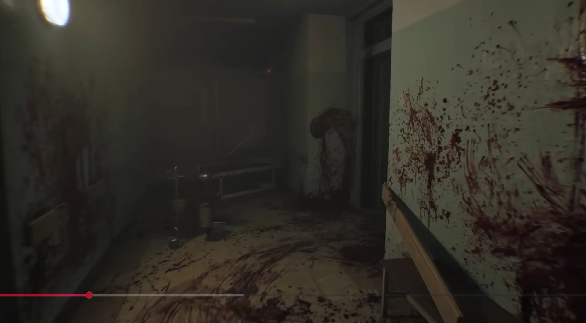Sala de hospital abandonada em ILL, com paredes e chão cobertos de sangue e um vulto disforme encolhido ao fundo