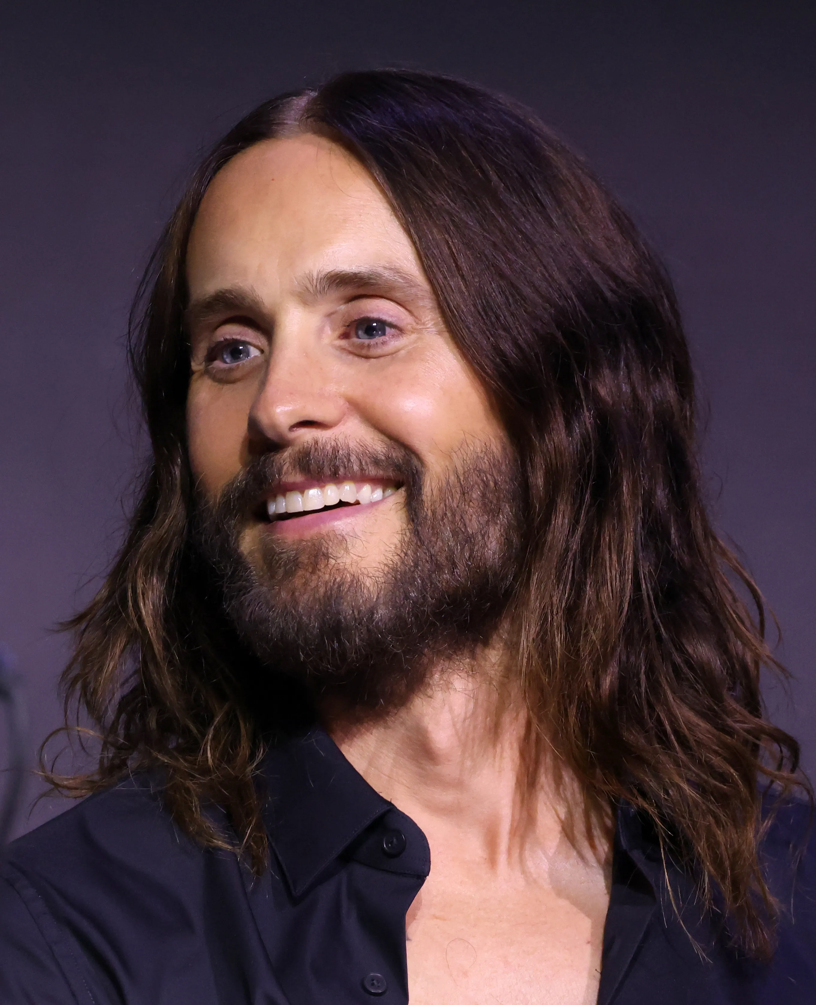 O ator Jared Leto fotografado de terno em um tapete vermelho, em close, olhando para a câmera