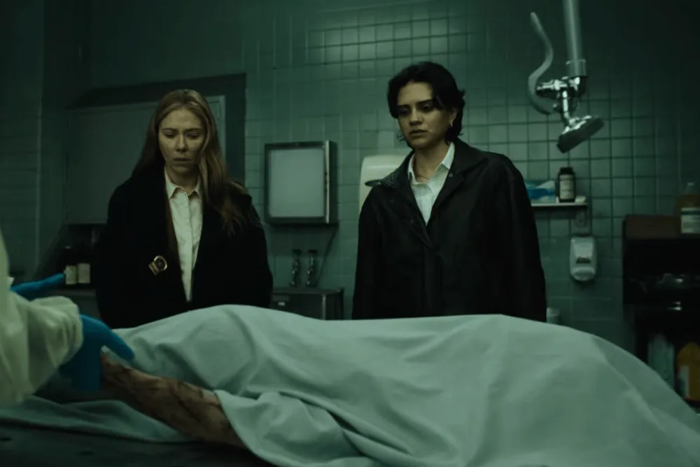 Scarlett Johansson e Sasha Calle, como as detetives Julie Miller e Gina Restrepo, diante de um corpo coberto num necrotério no trailer de O Exorcista: Mártires