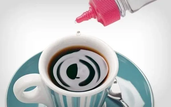 Gotejador de adoçante líquido despejando gotas em xícara de café preto