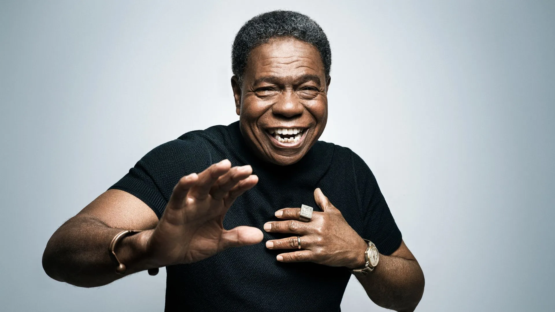 Paulinho da Costa sorrindo com as mãos em pose de percussionista, em retrato para a Rolling Stone Brasil