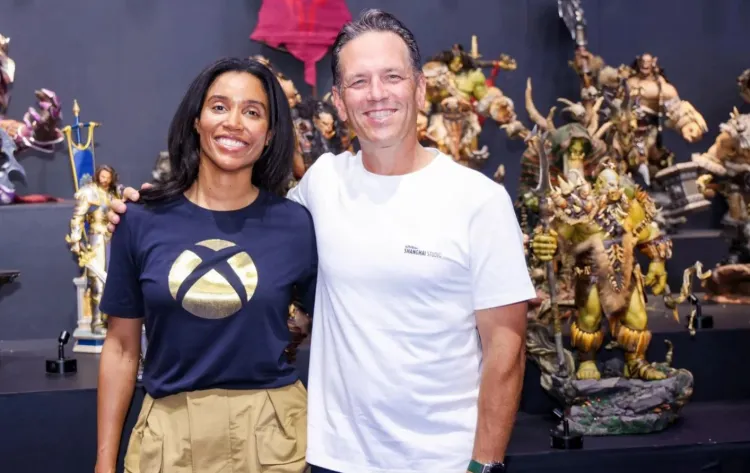 Sarah Bond e Phil Spencer lado a lado com miniaturas de personagens de jogos Xbox ao fundo