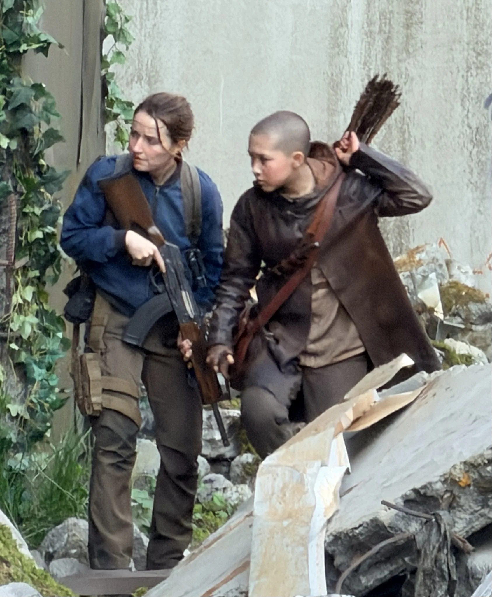 Kaitlyn Dever como Abby e Kyriana Kratter como Lev caminhando entre escombros no set de The Last of Us 3 em Vancouver